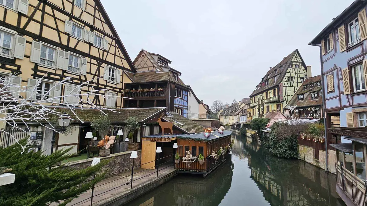 Petite Venise in Colmar on a grey day, half-timbered houses along the Lauch canal with a market chalet on the quay