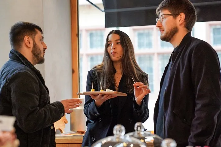 Three people tasting Alsatian food from a wooden board at a shop counter