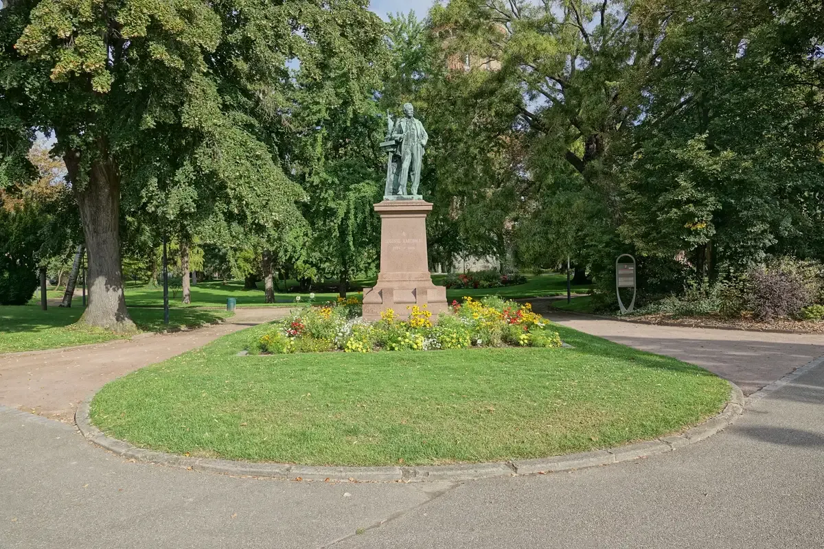 Monument to Auguste Bartholdi in a Colmar park with a flower bed