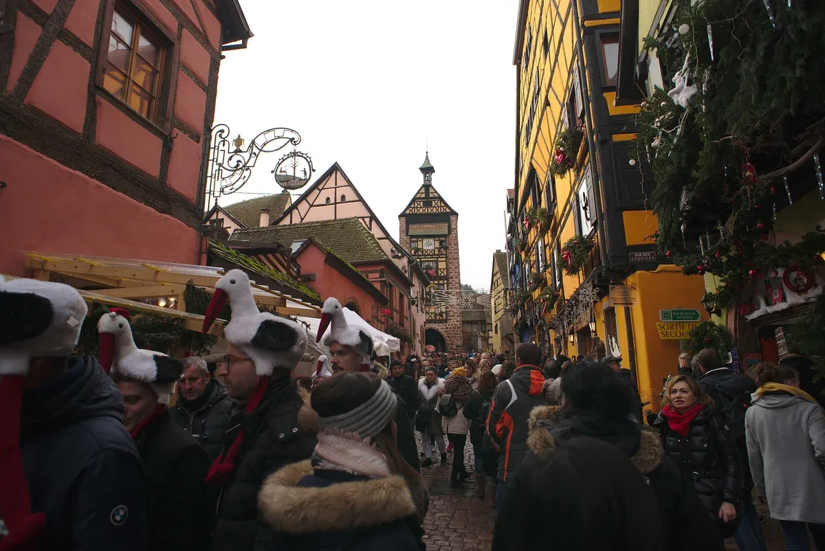 Crowd walking down the main street of Riquewihr toward the Dolder gate tower at the Christmas market